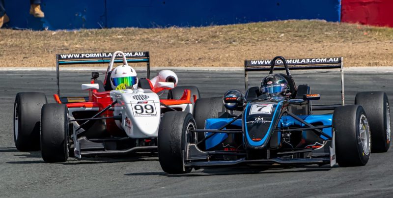Cars 7 & 99 duel for position in corner during formula 3 race at Queensland Raceway