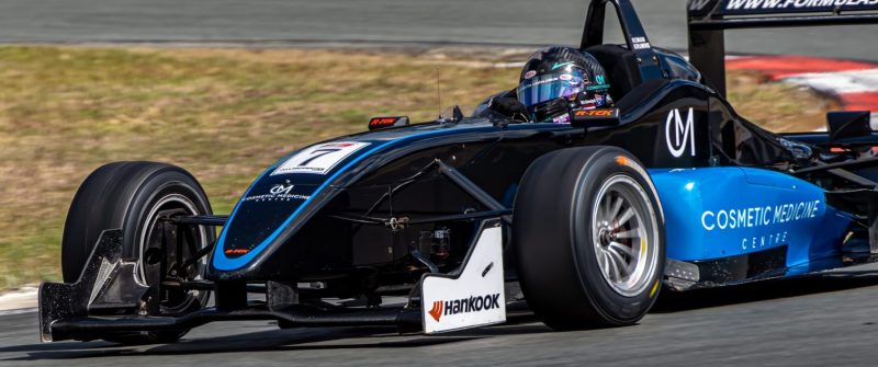 Black and blue Car 7 accelerating out of corner at Queensland Raceway om a formula 3 race